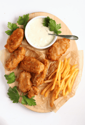 Finished recipe on a wooden platter with fries and tartar sauce