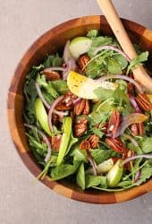 Curry Apple Salad in a salad bowl with wooden spoons