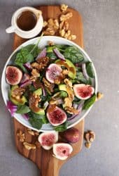 Finished salad on a wooden platter with fresh figs