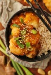 Baked Orange Cauliflower and rice in a black bowl with chopsticks