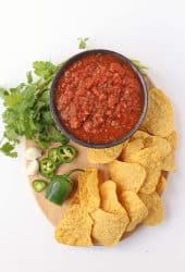 Homemade salsa on a wooden platter with tortilla chips