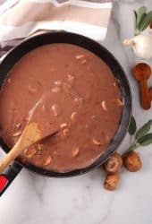 Finished gravy in a skillet with a wooden spoon