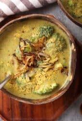 Bowl of homemade broccoli cheese soup on a wooden platter